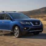 A blue 2017 Nissan Pathfinder is shown driving on a dirt road after viewing Certified Pre-Owned Nissan sales.