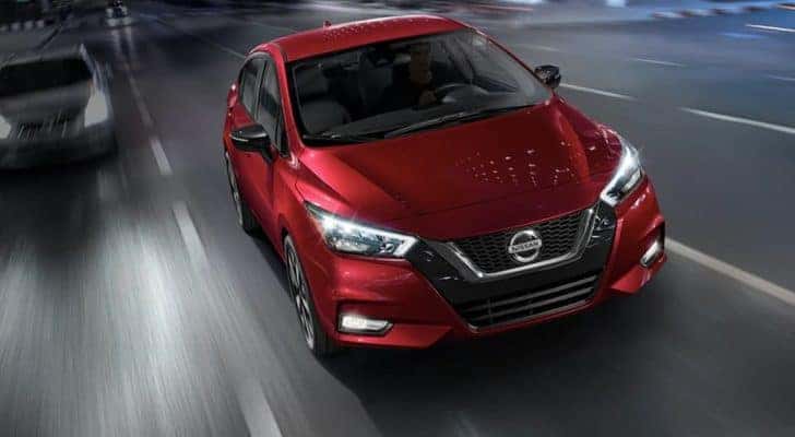 A red 2020 Nissan Versa is shown on a highway after viewing certified pre-owned Nissan sales.