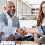 A couple is shown talking to a salesman about selling their car.