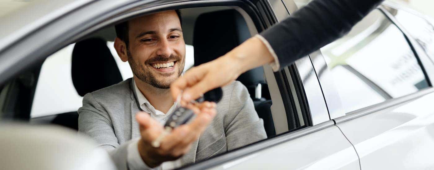A person is shown sitting in the drivers seat os a certified pre-owned vehicle.