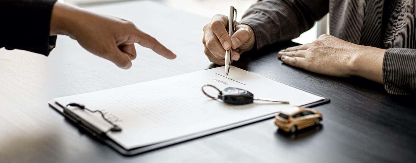 A salesperson is helping a customer to fill out paperwork at a Nashville used car dealer.