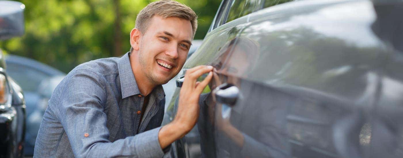 A person is shown looking at a car at a Nashville used car dealer.