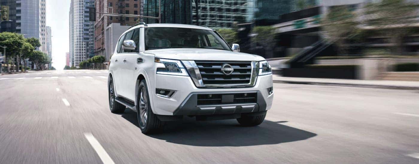 A white 2022 Nissan Armada is shown from the front driving through a city.