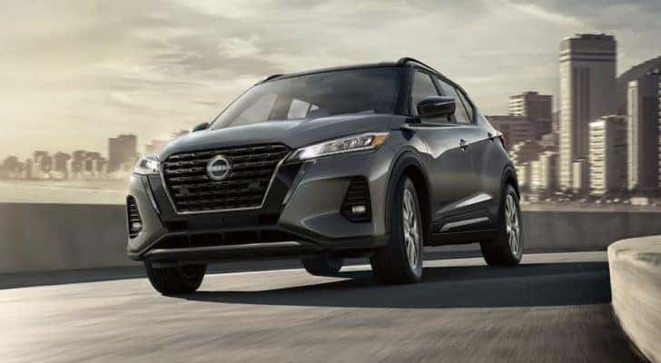 A grey 2022 Nissan Kicks is shown from the front driving through a city.