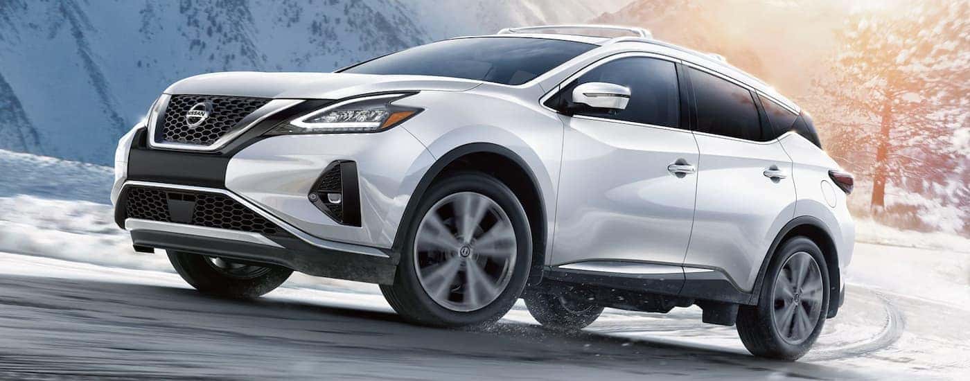 A white 2022 Nissan Murano is shown from the side driving on an open snow covered road.