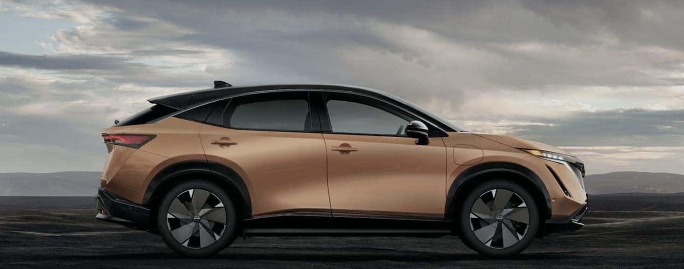 A gold 2023 Nissan ARIYA is shown from the side.