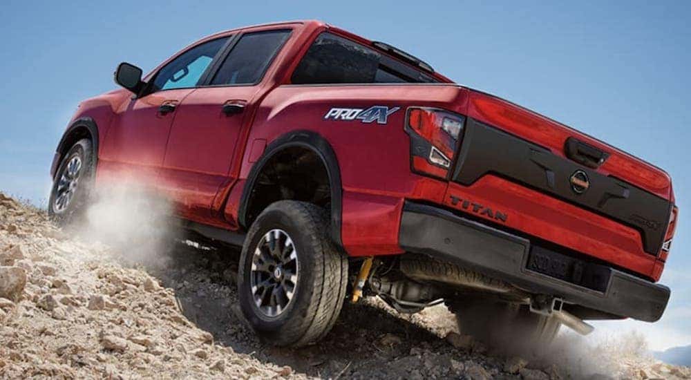 A red 2022 Nissan Titan Pro4x is shown from behind at a low angle while driving off-road after leaving a Nissan Titan dealer.