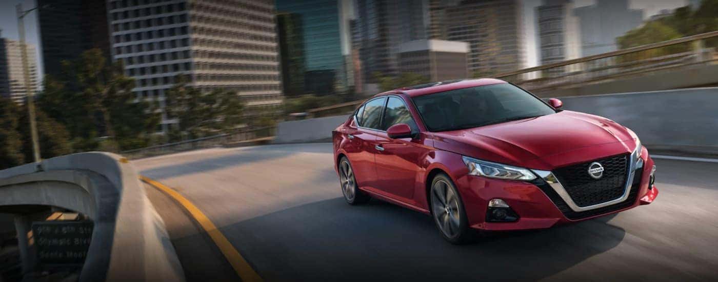 A red 2021 Nissan Altima is shown from the front while crossing a bridge.