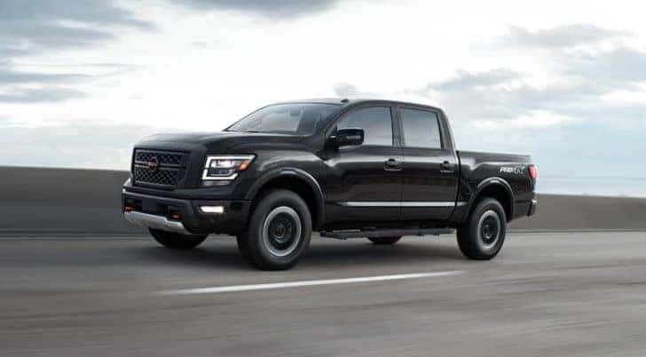A black 2021 Nissan Titan is shown from the side while driving on the highway after leaving a dealer that had certified Nissan for sale.