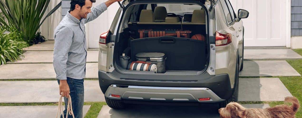 A person is shown taking gear out of the rear cargo area of a 2023 Nissan Rogue Platinum.