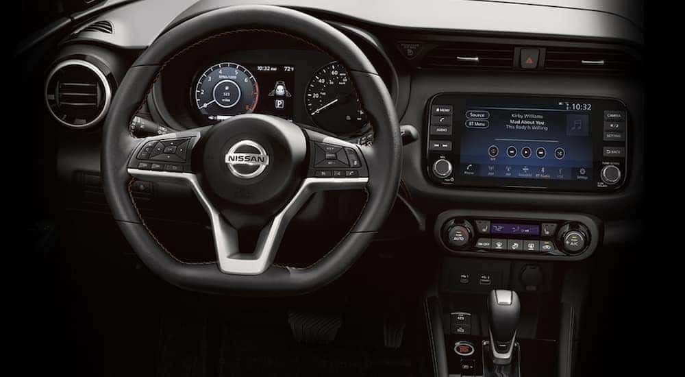 The black interior of a 2021 Nissan Kicks with digital dash and infotainment screen.