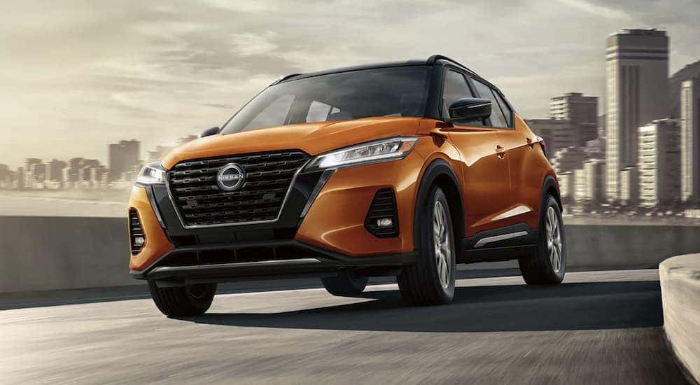 An orange 2022 Nissan Kicks driving away from a city