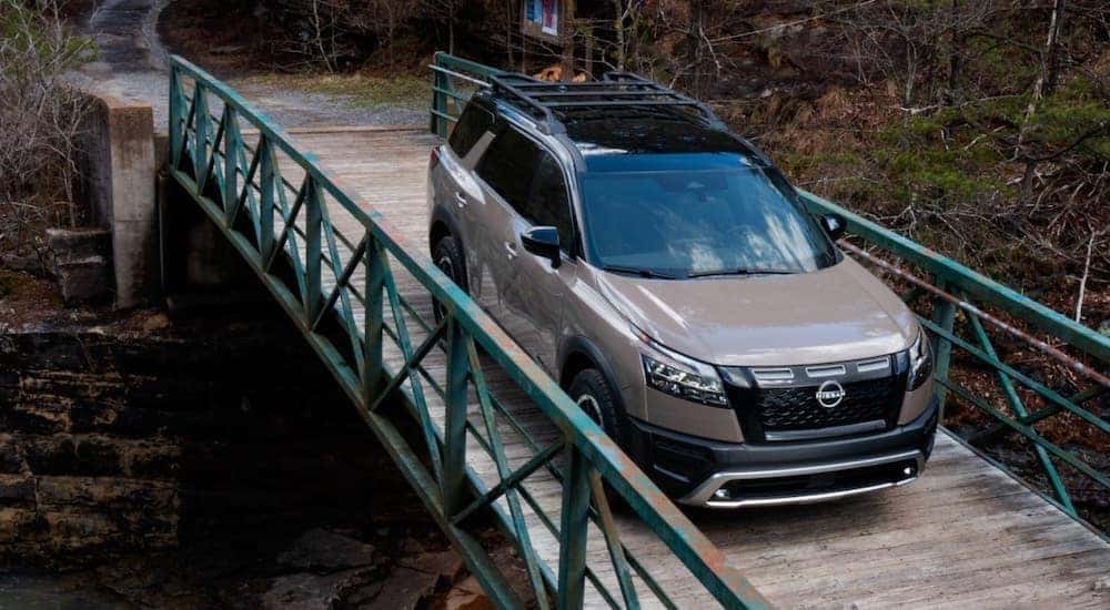 Overhead view of a brown 2023 Nissan Pathfinder Rock Creek crossing a small wooden bridge.