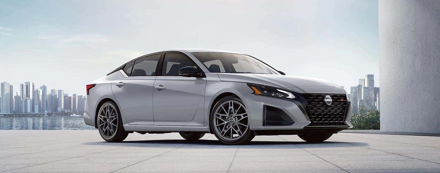 A white 2023 Nissan Altima is shown from the front after leaving a dealer that handles Nissan Altima sales.
