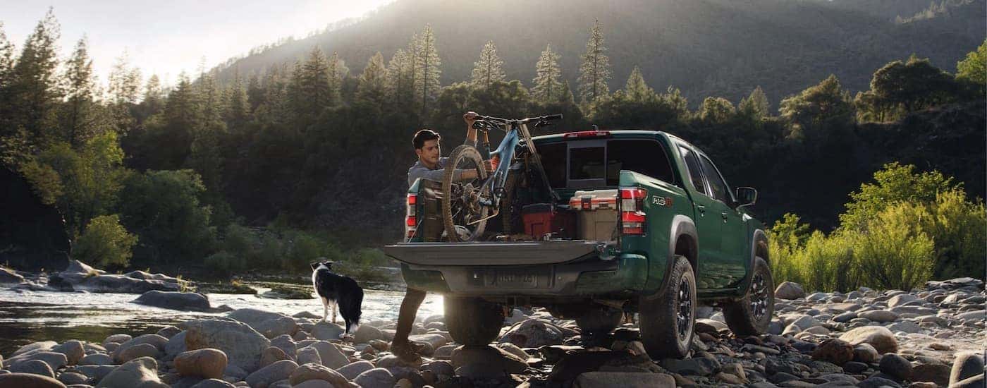 A green 2023 Nissan Frontier Pro-4x is shown from the rear with items in the bed.