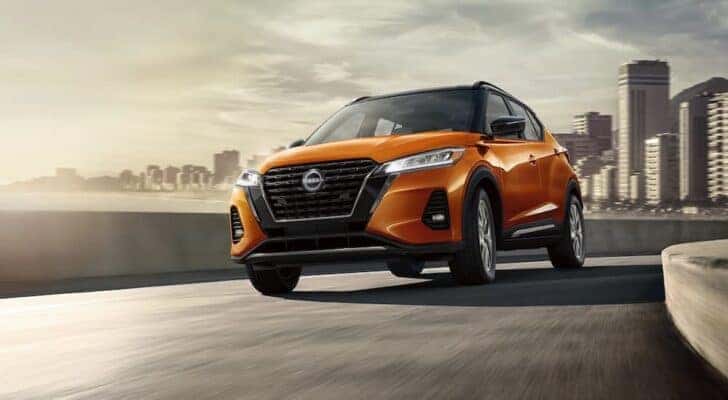 An orange 2023 Nissan Kicks is shown from the front at an angle on an offramp.