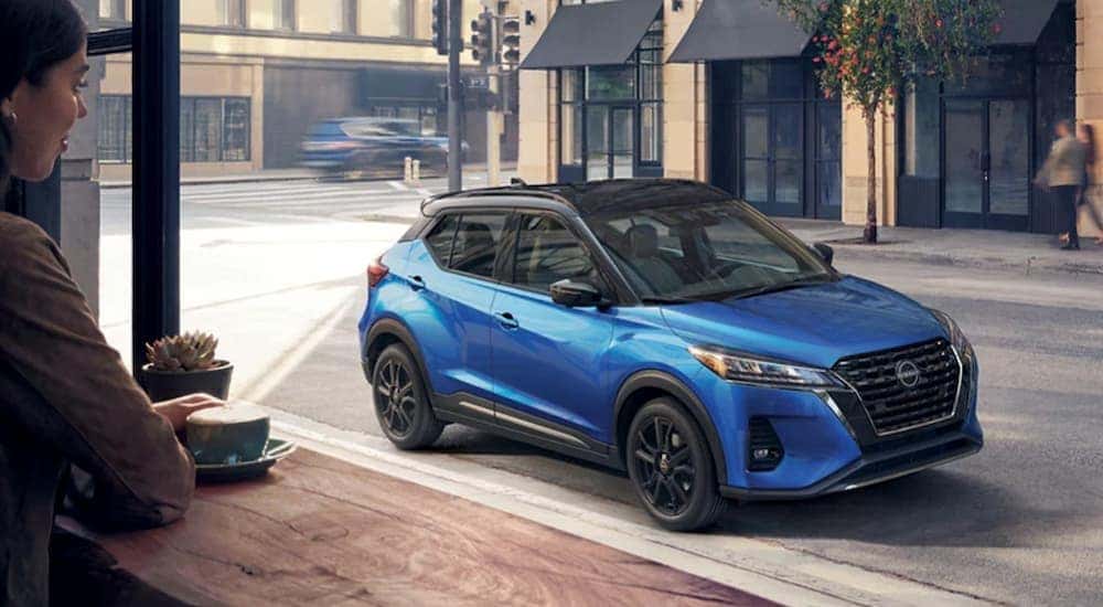 A blue 2023 Nissan Kicks SR is shown parked near a café after visiting a Nissan Kicks for sale.