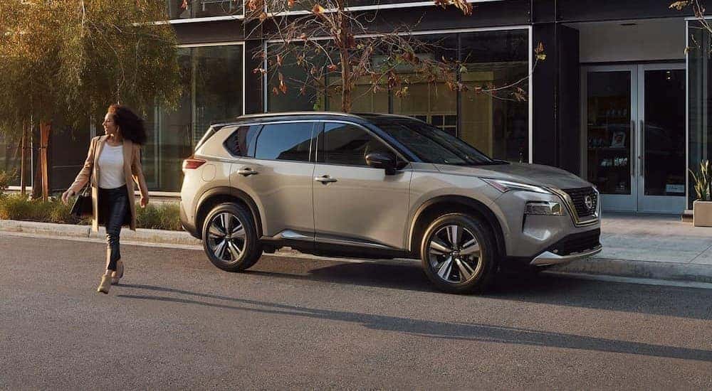 A popular Nissan Rogue for sale near Lewisburg, a silver 2023 Nissan Rogue Platinum, is shown parked near a person crossing a street.