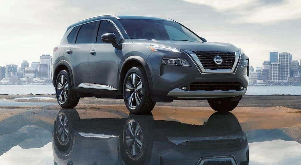 A silver 2023 Nissan Rogue SV is shown parked near a city.