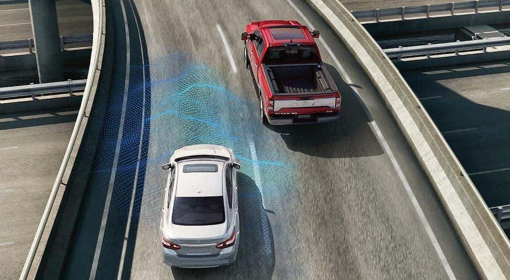 A red 2024 Nissan Titan is shown driving on the road, demonstrating its safety technology.