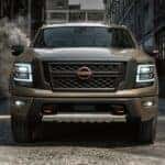 A popular Nissan Titan for Sale Near Lewisburg, a brown 2024 Nissan Titan PRO-4X, is shown parked near several buildings.