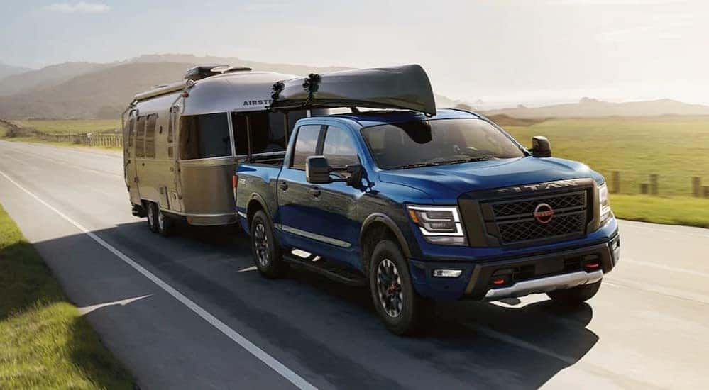 A blue 2024 Nissan Titan is shown towing an Airstream trailer.