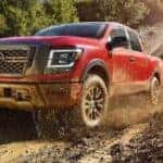 A popular Nissan Titan for Sale Near Lewisburg, a red 2024 Nissan Titan PRO-4X, is shown driving off-road.