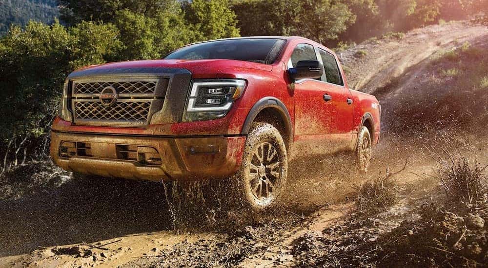 A popular Nissan Titan for Sale Near Lewisburg, a red 2024 Nissan Titan PRO-4X, is shown driving off-road.
