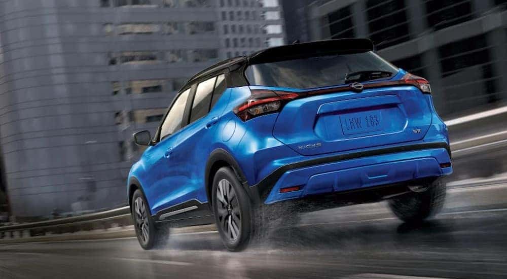 A blue 2024 Nissan Rogue SR is shown driving on a wet road.