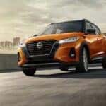 A common Nissan Kicks for sale near Columbia, an orange 2024 Nissan Kicks, is shown driving near a city.