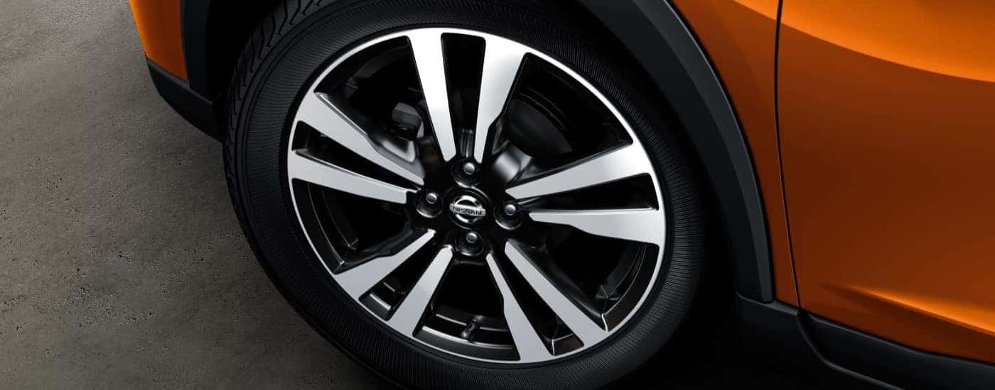 A close up shows a wheel on an orange 2018 Nissan Kicks.