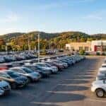 Row of new Nissan SUVs and a Frontier pickup on a dealership lot in early autumn