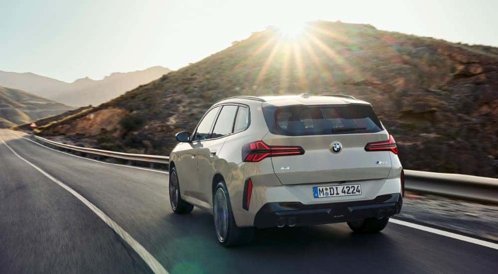 A tan 2025 BMW X3 M50 is shown from the rear at an angle.
