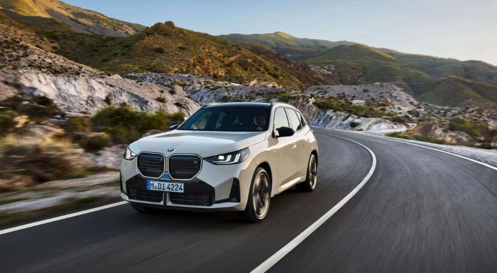 A tan 2025 BMW X3 M50 is shown from the front after leaving a BMW dealer.