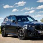 A black 2025 BMW X5M is shown from the front at an angle after leaving a BMW dealer.