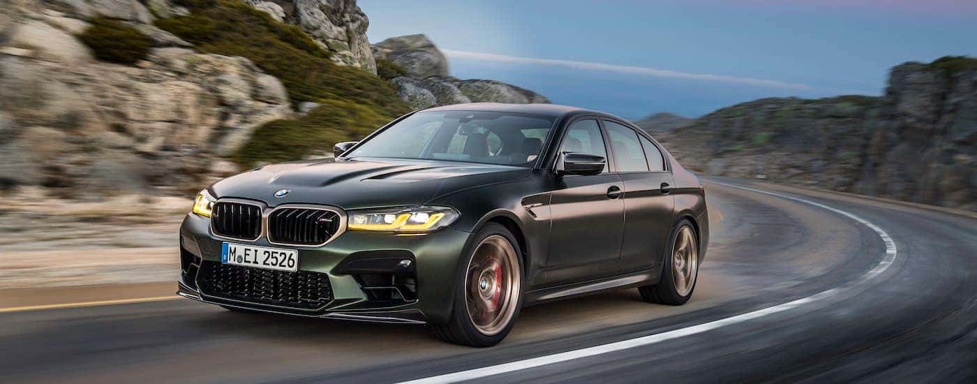 A green 2022 BMW M5 is shown from the front at an angle. after leaving a dealer that has used BMWs for sale.
