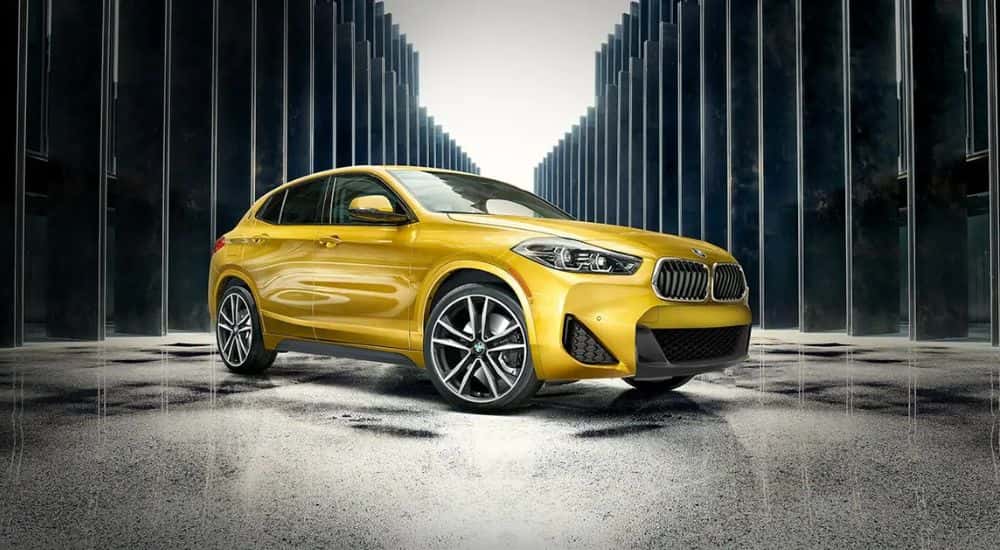 A yellow 2022 BMW X2 M35i parked in front of modern architecture.