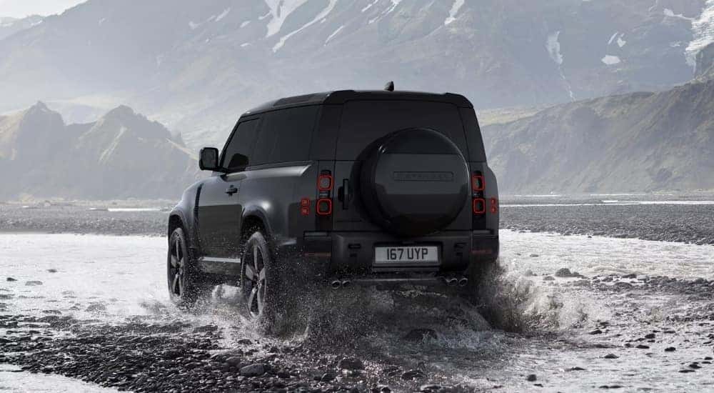 A black 2025 Land Rover Defender 90 is shown from the rear at an angle.