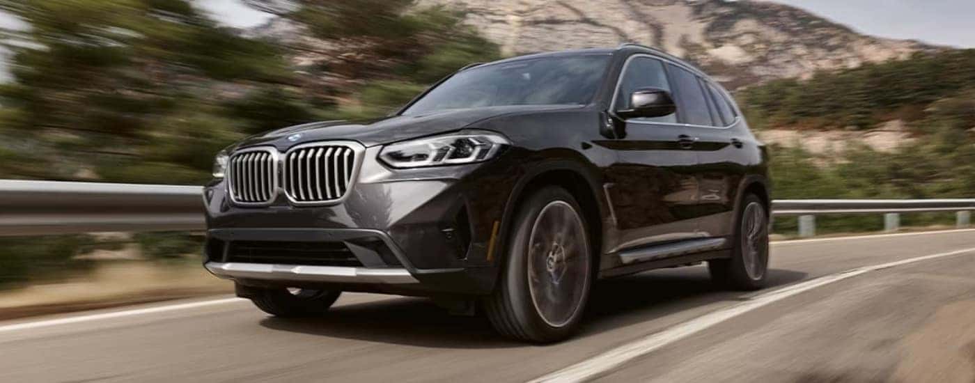 A grey 2024 BMW X3 for sale driving on an open road.