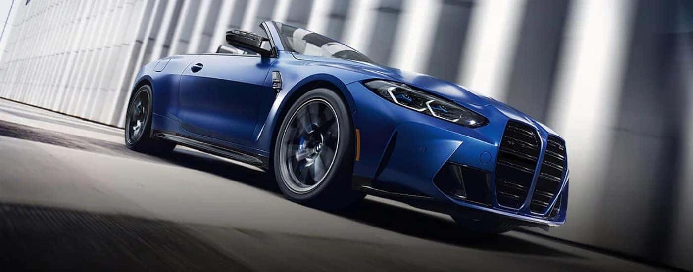 A blue 2022 BMW M4 driving past concrete pillars.