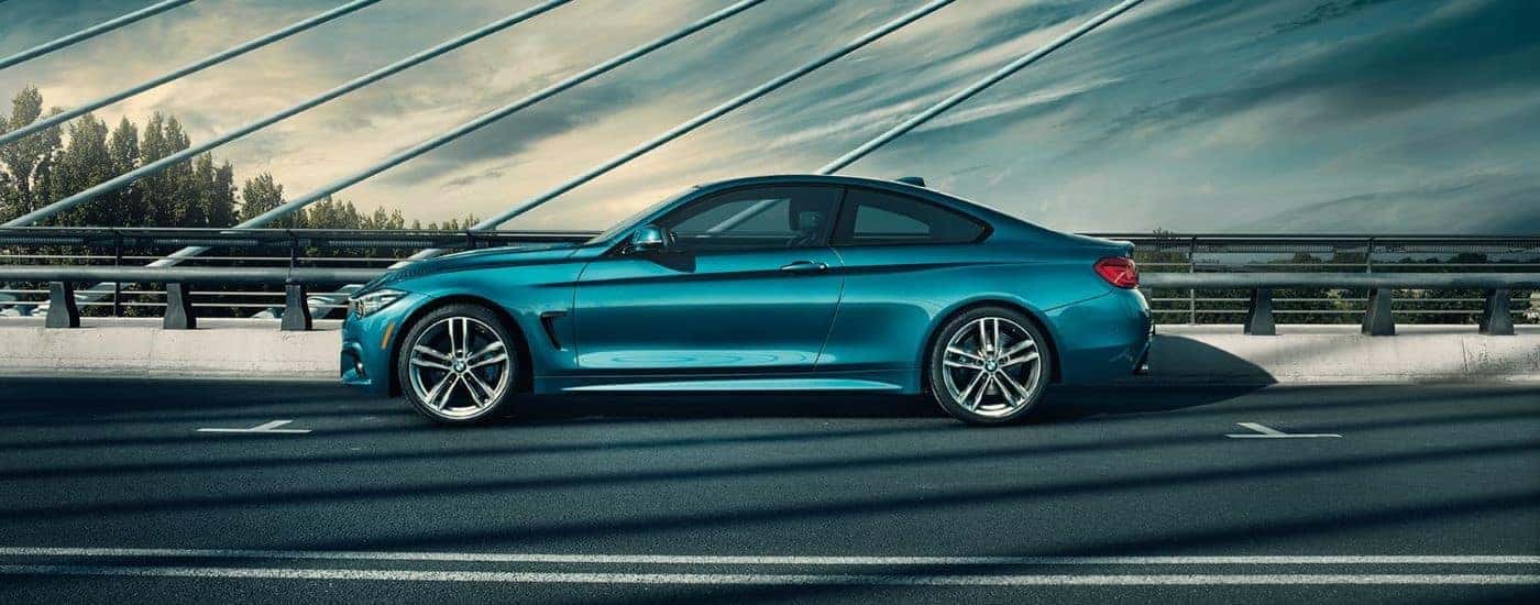 A green 2019 BMW 4 Series driving on a bridge.