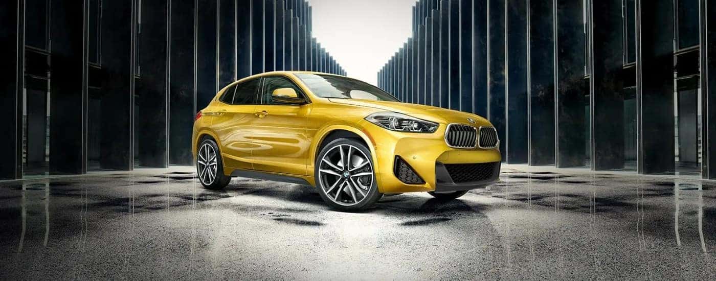 A yellow 2022 BMW X2 M35i parked on a wet surface.