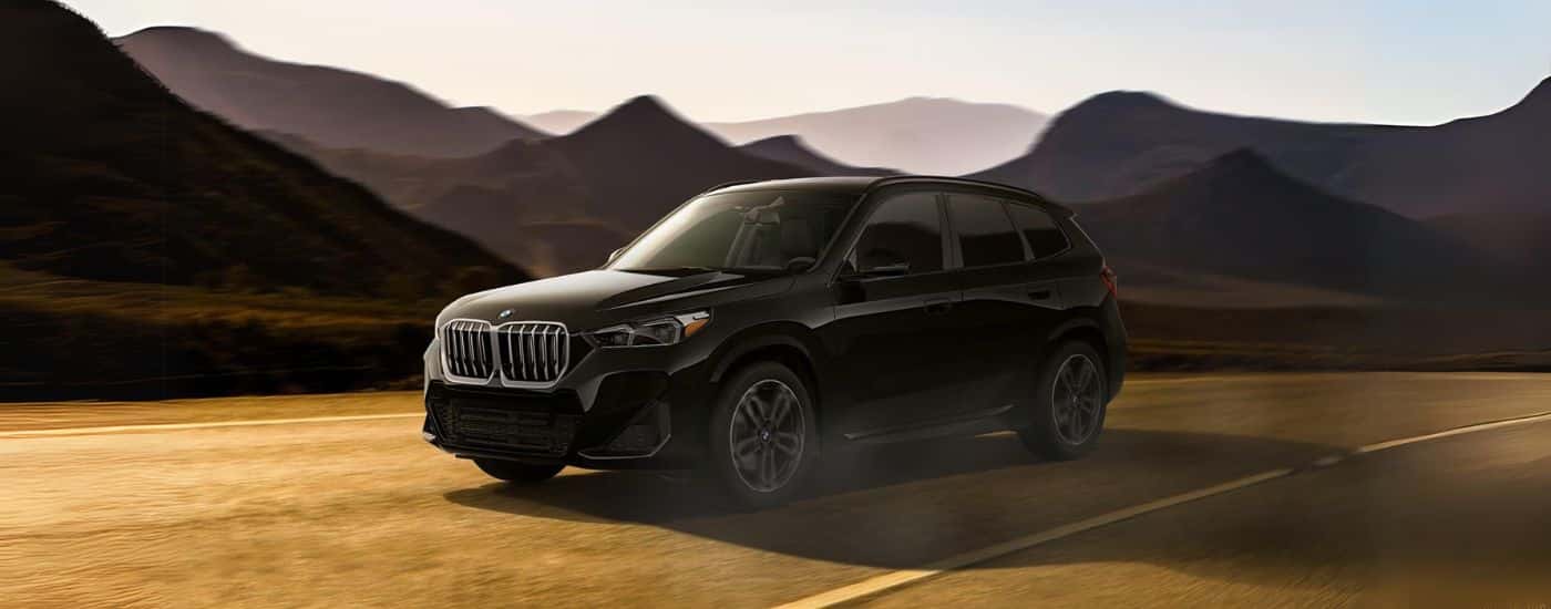 A black 2024 BMW X1 driving to view a used BMW for sale in Omaha.