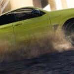 A yellow 2024 BMW X4 M performing a burnout.