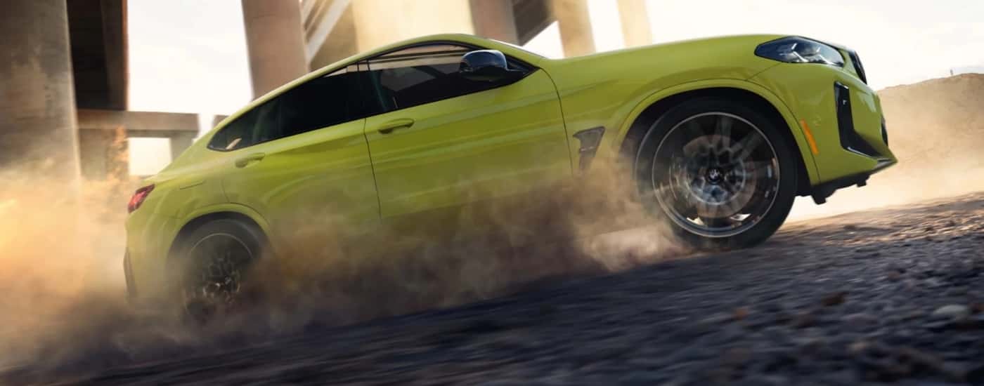 A yellow 2024 BMW X4 M performing a burnout.