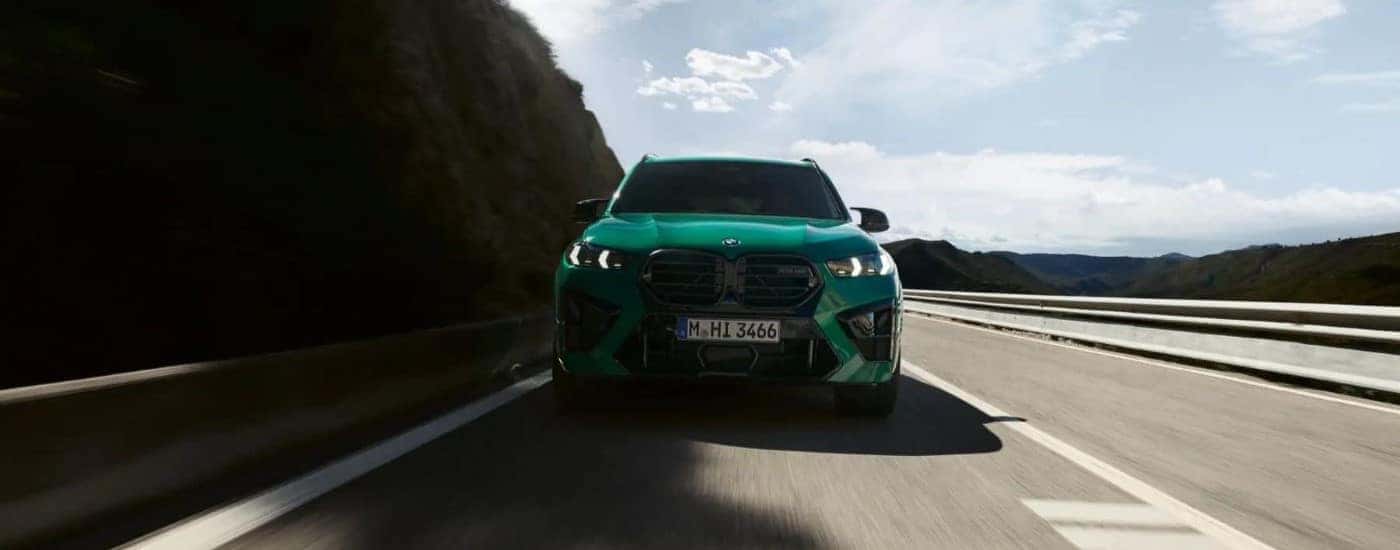 A green 2024 BMW X5 M driving on a highway
