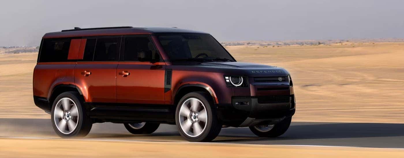 An orange 2025 Land Rover Defender from the side.