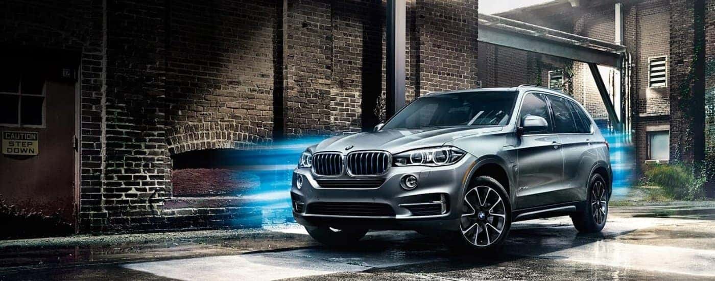 A silver 2018 BMW X5 parked near a brick building.