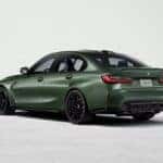A green 2026 BMW M3 sedan parked in a showroom.