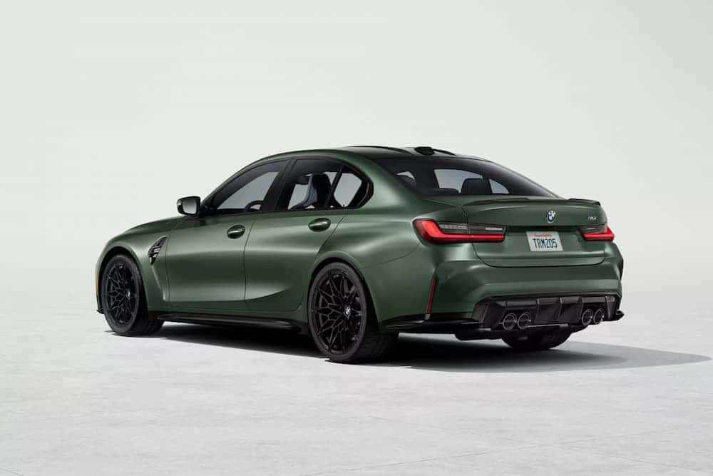 A green 2026 BMW M3 sedan parked in a showroom.